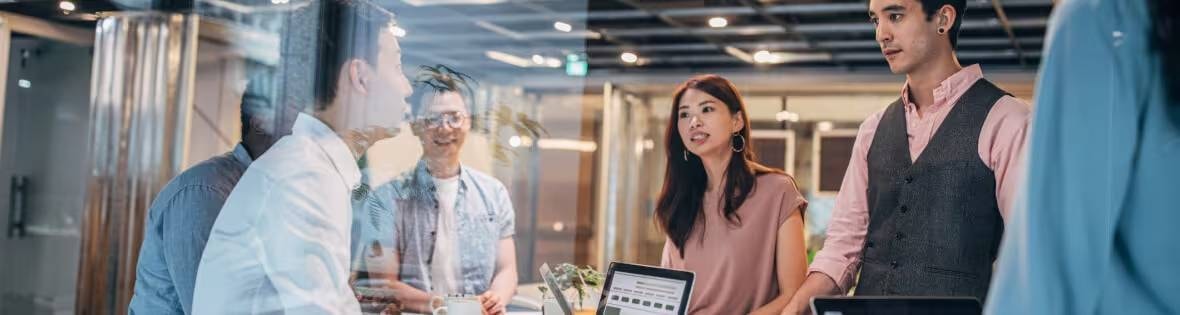 Fotografía de profesionales conversando en una oficina, que ilustra el artículo de Oracle NetSuite sobre las 16 métricas SaaS esenciales para realizar un seguimiento de los ingresos y el crecimiento, las ventas, el marketing y el éxito del cliente.